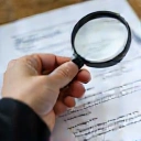 Mano che tiene una lente d'ingrandimento su un documento, simbolo di trasparenza